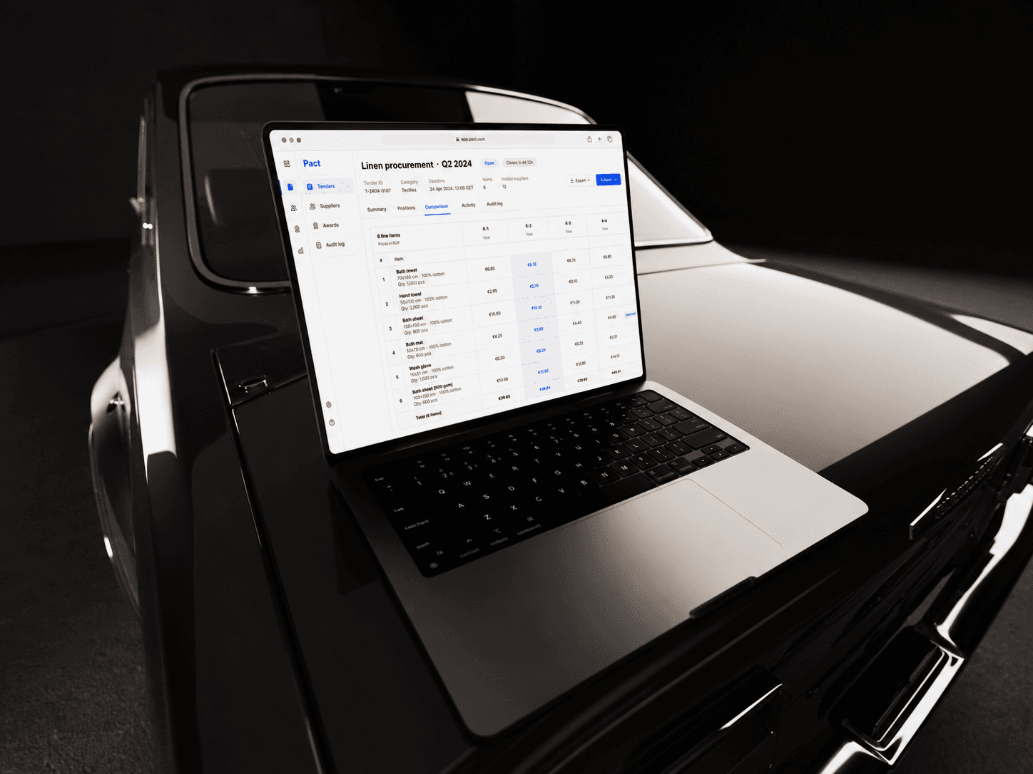 Pact procurement platform on a MacBook resting on the hood of a black car under one hard key light, showing a linen tender compared across four supplier columns.